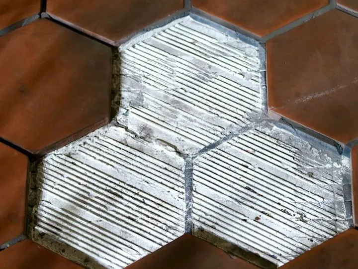 Piso cerâmico com peças soltas mostrando a argamassa — descolamento de revestimento diagnosticado em inspeção predial