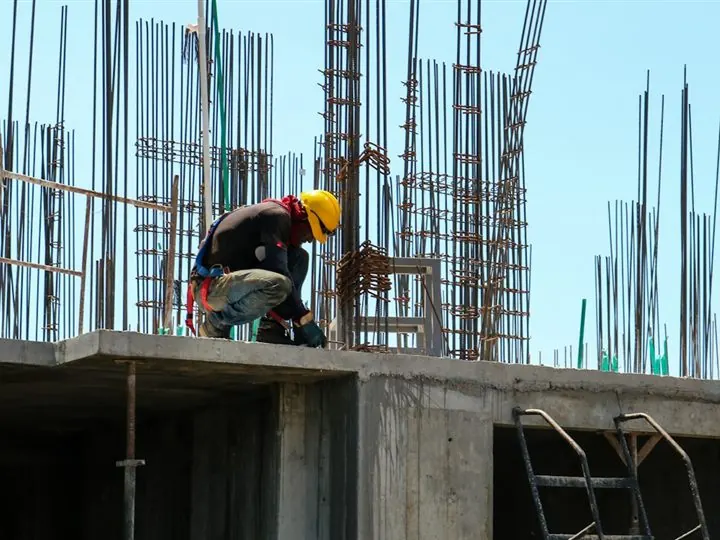 Trabalhador em estrutura de concreto armado com ferragens à mostra — obra vizinha que pode causar danos, vistoria cautelar em Uberlândia
